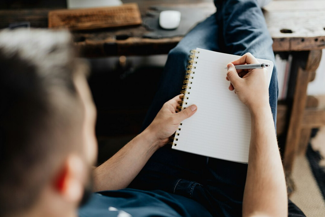 man writing notes in meeting